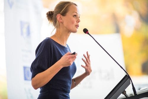 Woman speaking to a group photo for crisis communications post